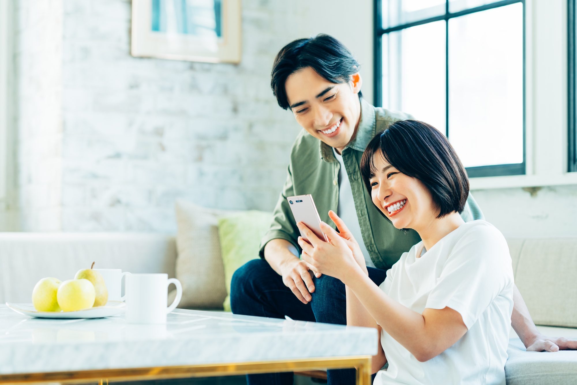 リビングでスマホを見る若い夫婦